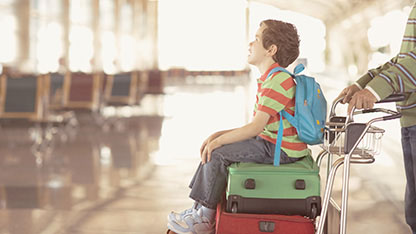 Boy sitting on suitcase at airport Boy sitting on suitcase at airport