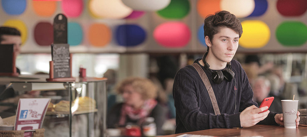 Young man paying for coffee using his mobile